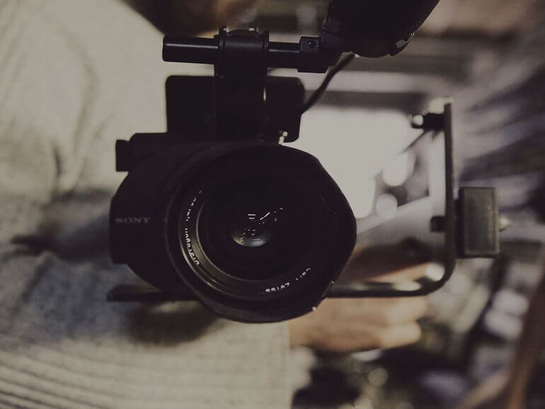 Camera held by a man in a beige sweater
