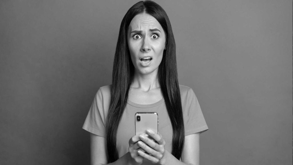 Une femme surprise par le contenu de son téléphone, représentant des followers découvrant que leur influenceur préféré a de faux abonnés.